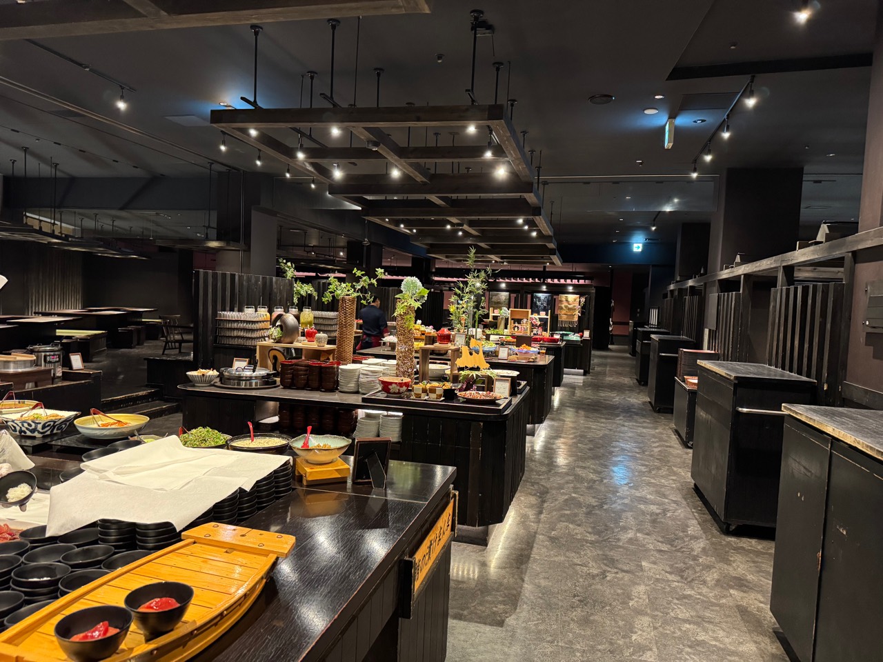 黒い木材を基調に料理台が並ぶ、のれそれ食堂のビュッフェ会場