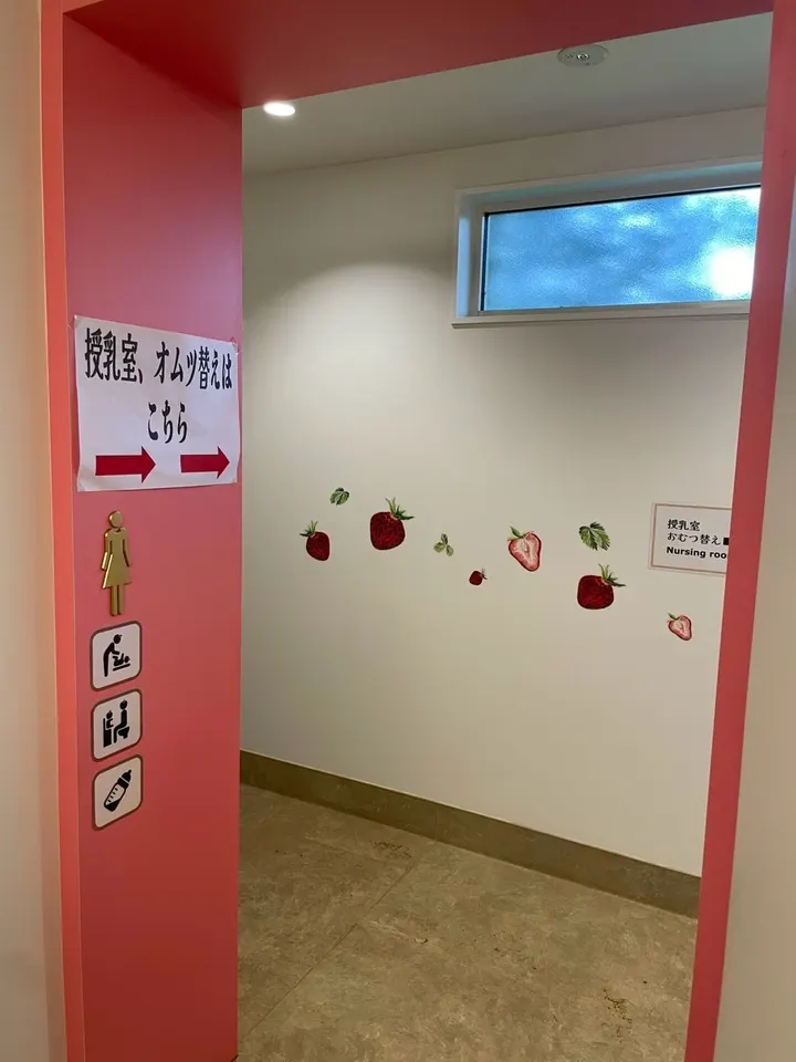 「授乳室、オムツ替えはこちら」と書かれた案内と、いちごの装飾がある通路