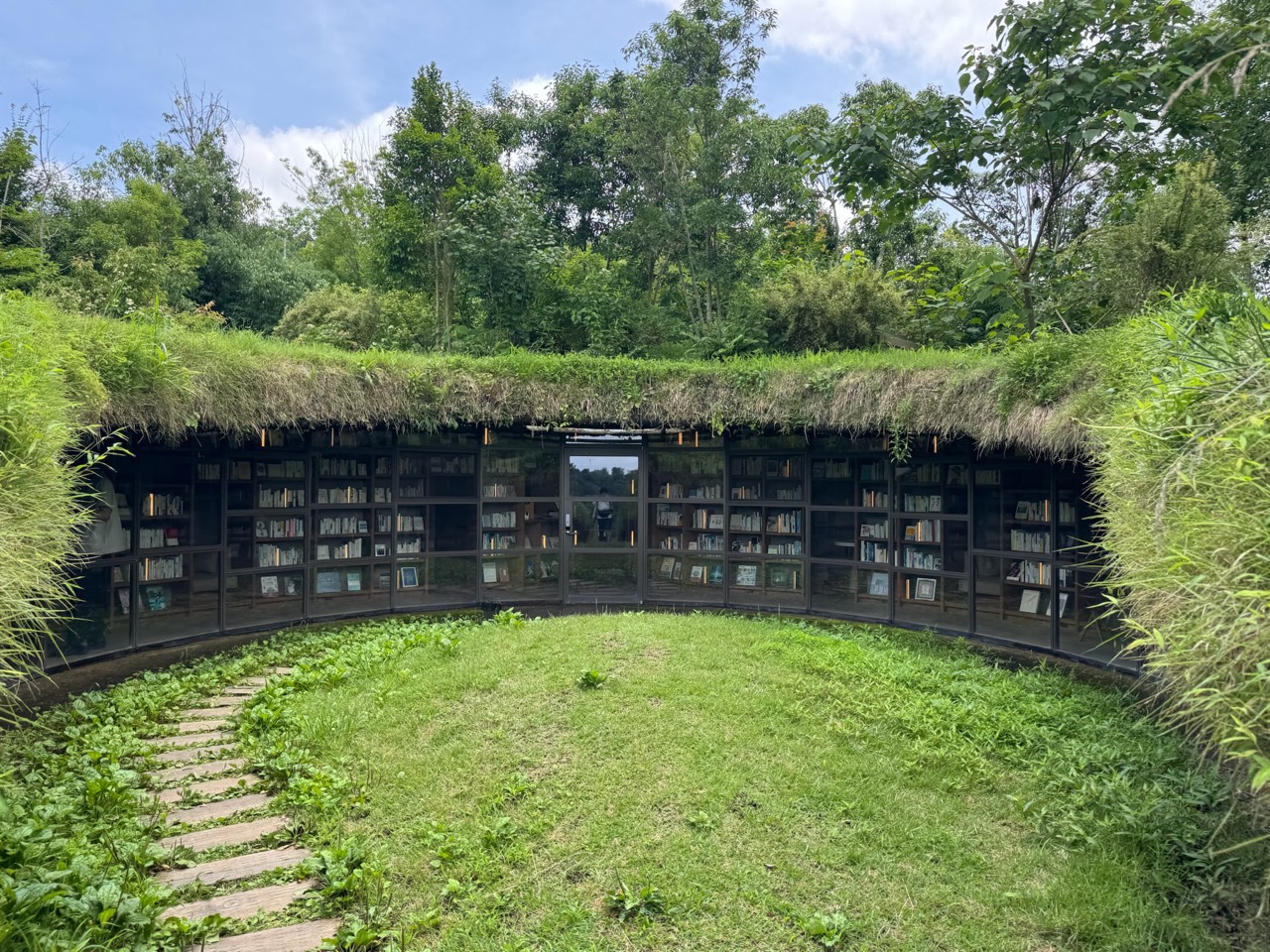 草で覆われた屋根の下に弧を描くように本棚が並ぶ地中図書館