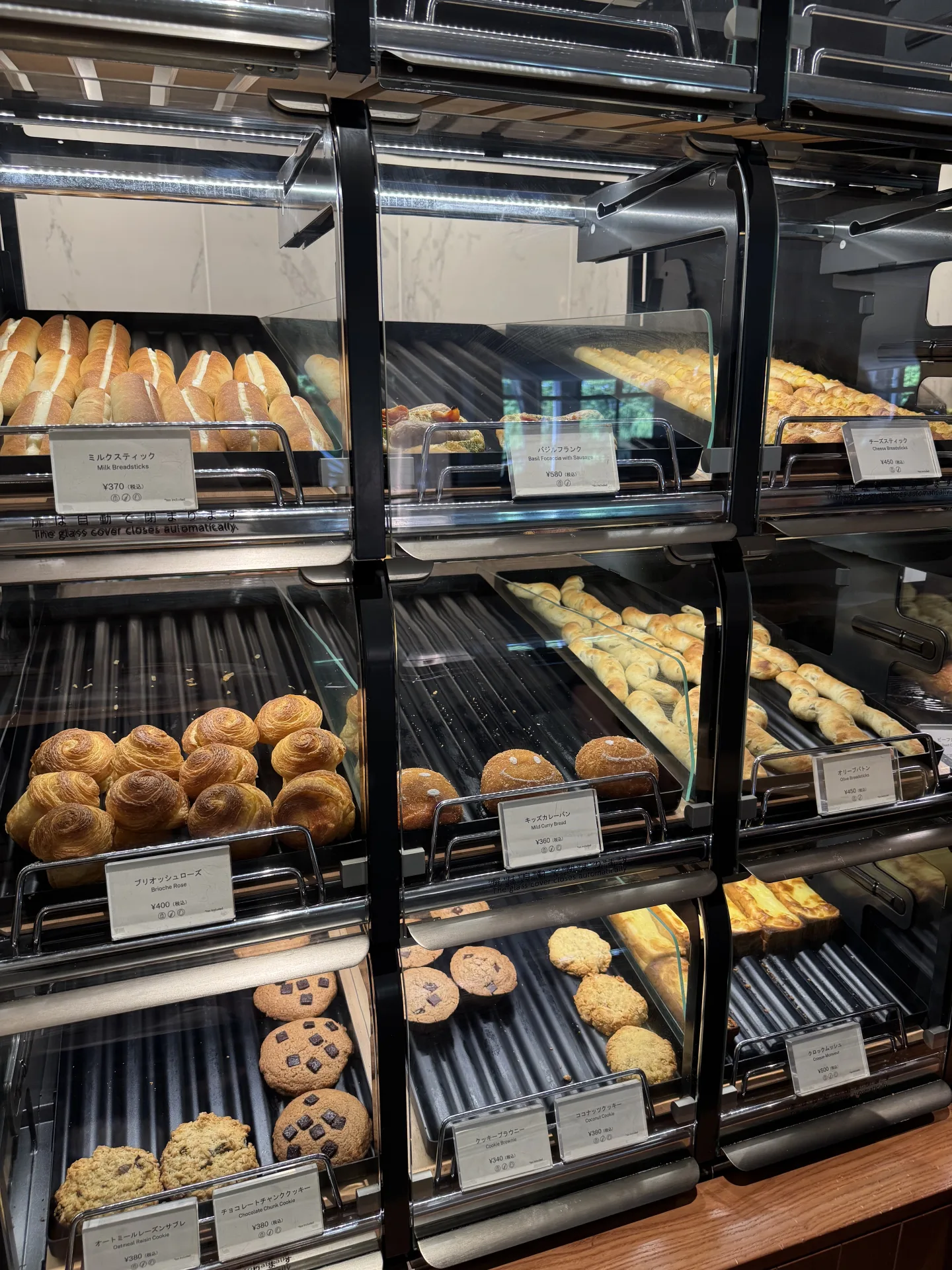OMO Bakeryの棚に並ぶ食事パン、カレーパン、ブリオッシュ、クッキー